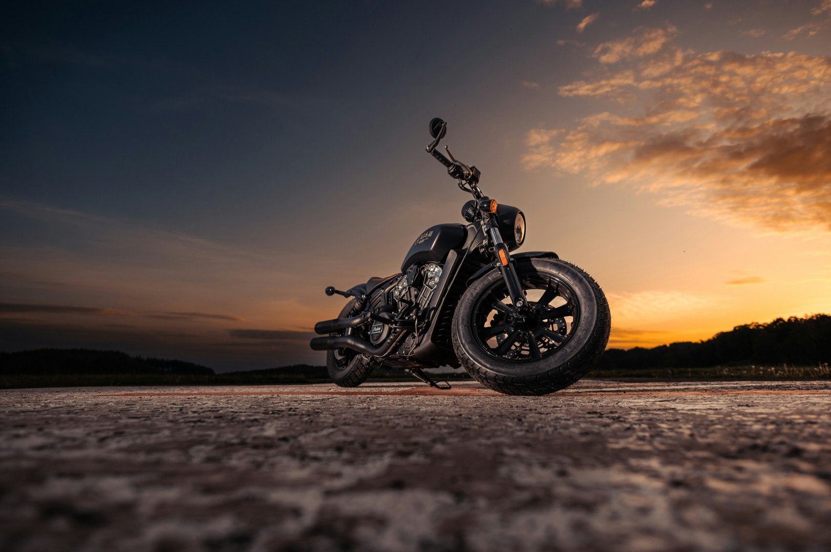 Motorcycle parked on a road at sunset